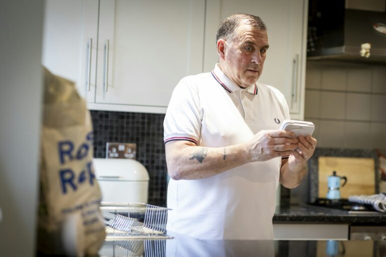 Man bekijkt zijn energieverbruik op zijn telefoon in de keuken