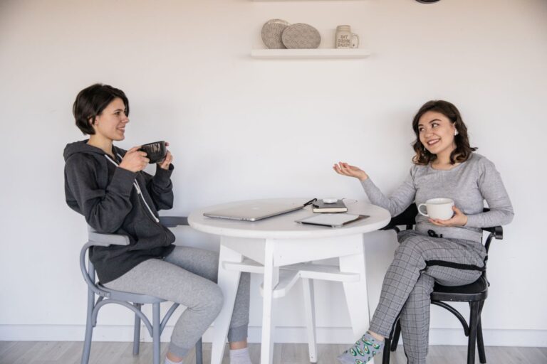 Twee vriendinnen praten met elkaar aan een tafel met koffie