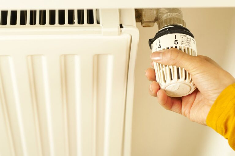 Hand draait aan de thermostaatknop van een radiator