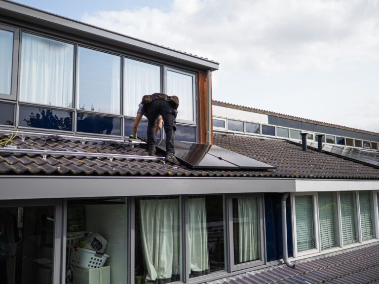 Installateur legt zonnepanelen op een schuin pannendak